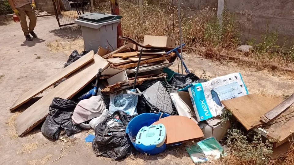 Antes del retiro de escombros en patio con contenedor gris lleno de material de demolición en Santiago