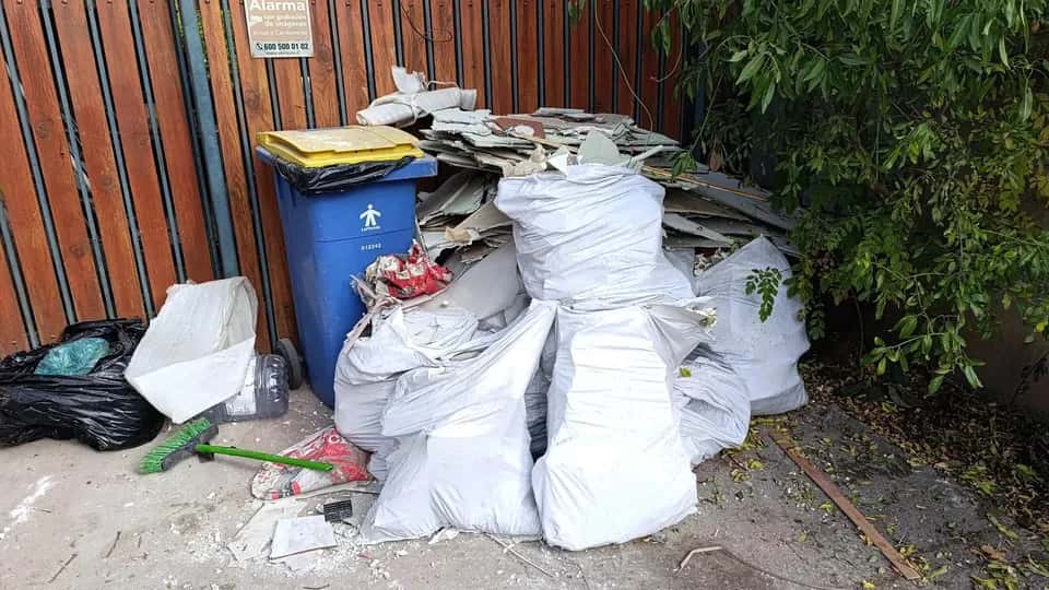Antes del retiro de escombros en entrada con portón de madera en Santiago